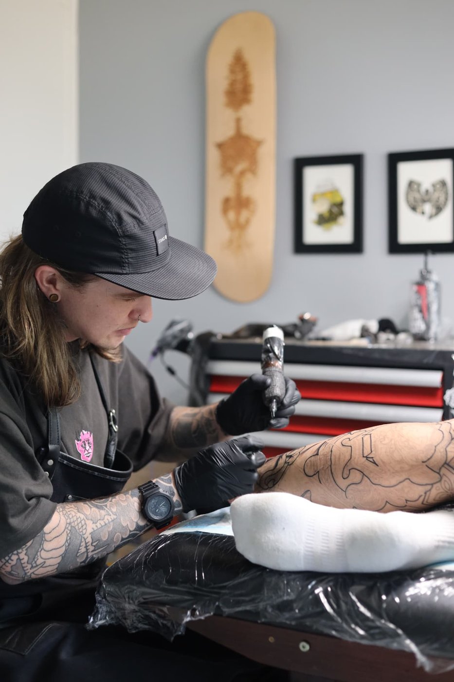 Rodwin Proctor tattooing a client against a slate wall